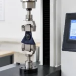 Pull Test Machine holding a garment button in a test fixture during an attachment strength test